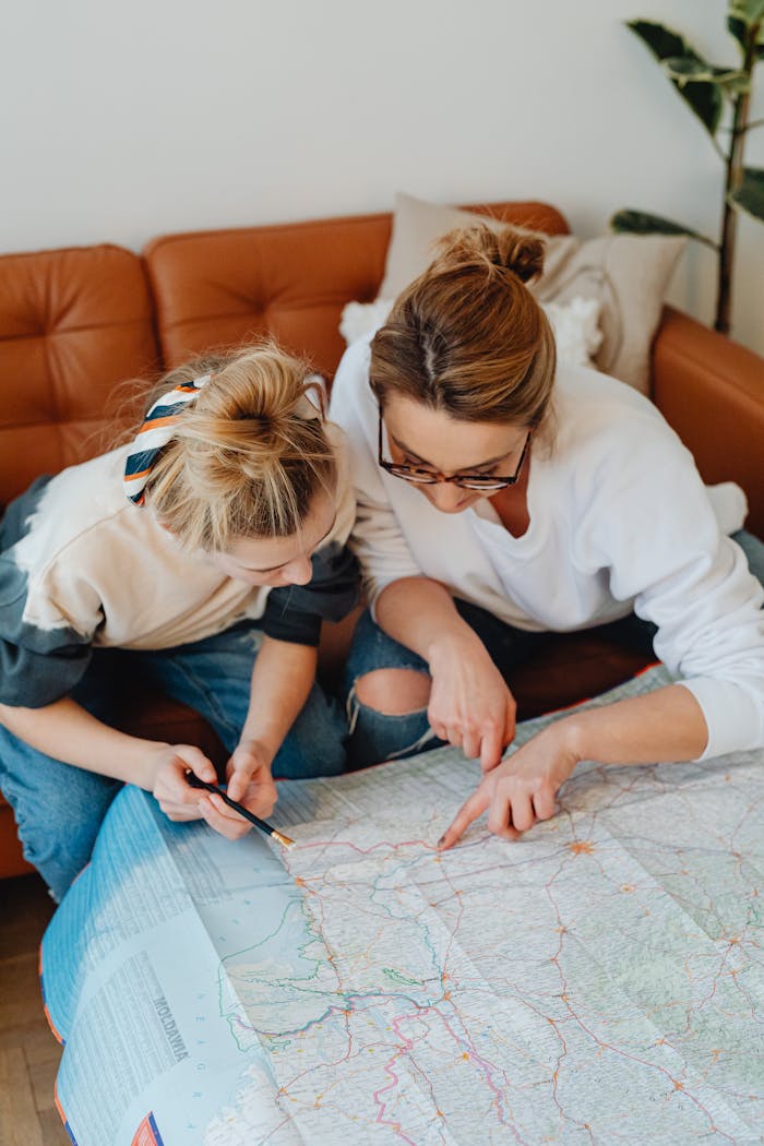 A mother and daughter planning their travel route while sitting at home with a map.